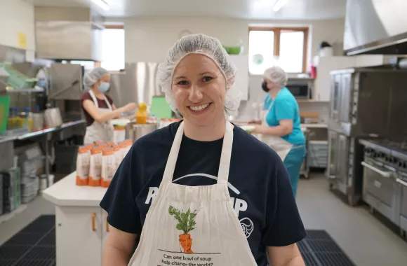 woman wearing hairnet and apron stands in kitchen