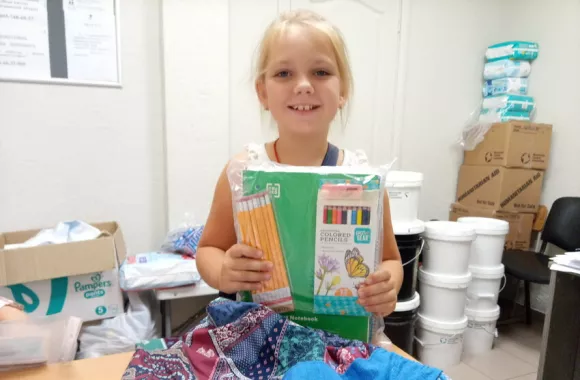 A photo of a young girl receiving school supplies