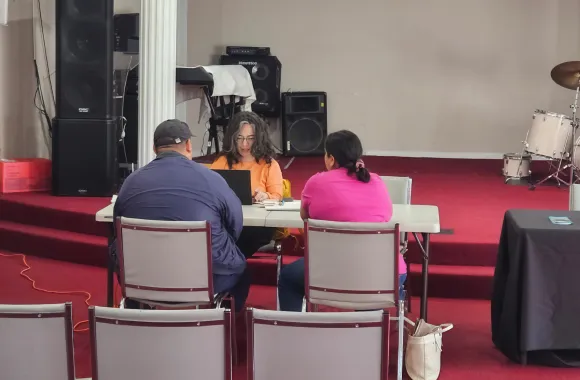 A couple sits at a table talking with a counselor.