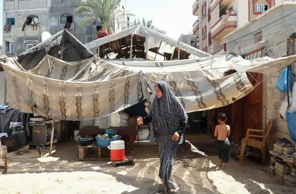 Andaleeb Abu Al Qumbuz walks from the makeshift shelter she shares with other family members in Gaza.