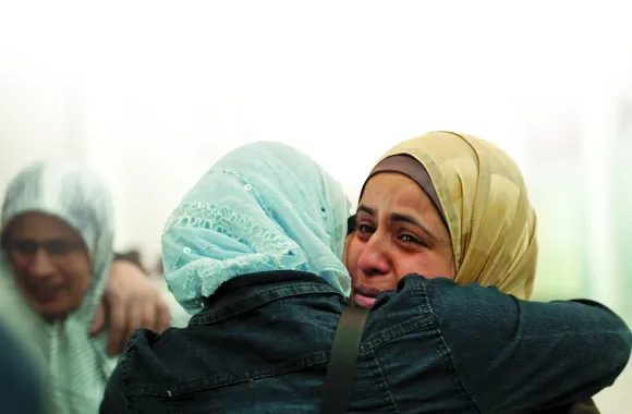 Two people in head coverings share an emotional embrace.