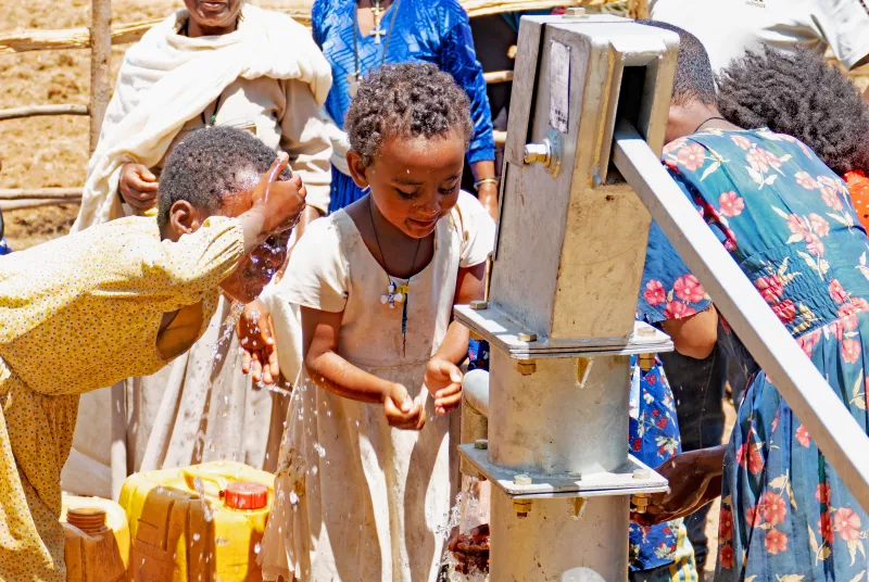 Wells and full cost.jpg Group of children at a well.