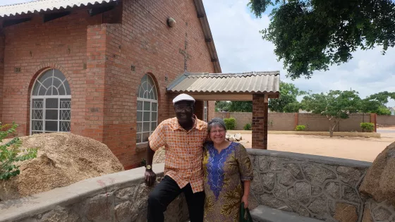 A man and a woman stand in front of a brick church 