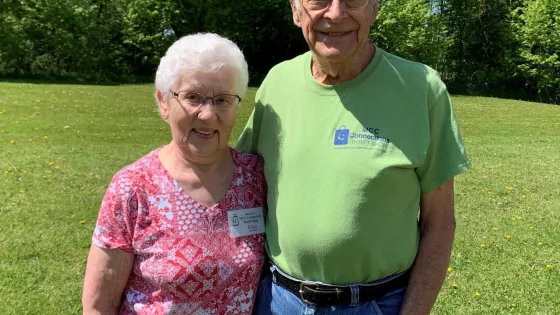 An older woman and man stand in a grassy space