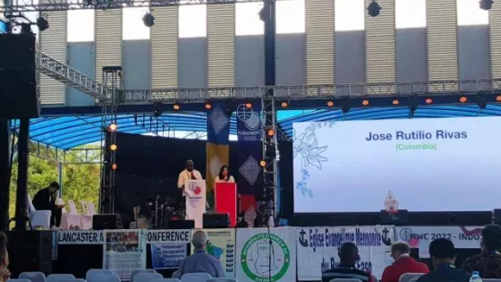 Two people stand at podiums on stage 