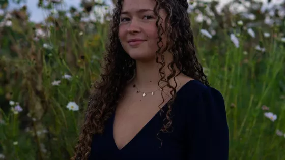 Allison sitting for a photo in front of a field