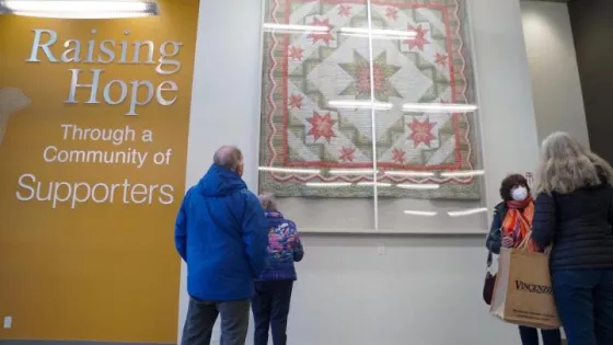 People looking at a hanging quilt