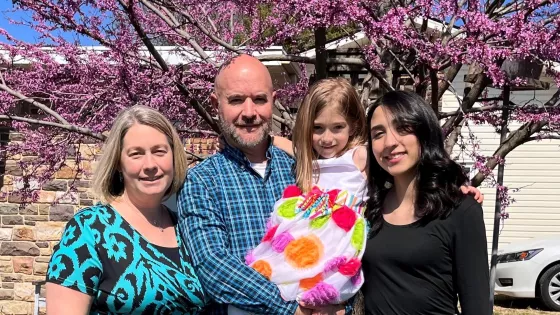 A woman, man child and young woman standing for a photo