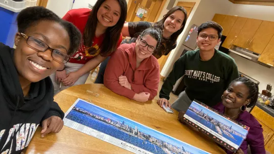 A group of people posing for a photo by a set of puzzle.