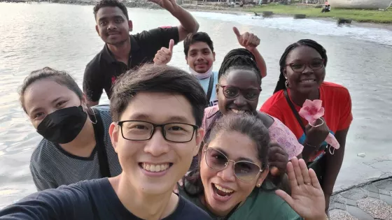 A group of seven people of different nationalities take a selfie together.