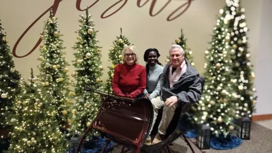 Three people sitting in a sleigh with Christmas decor