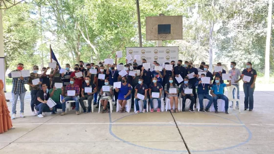 A large group of people at a graduation ceremony. They are all holding their diplomas. 