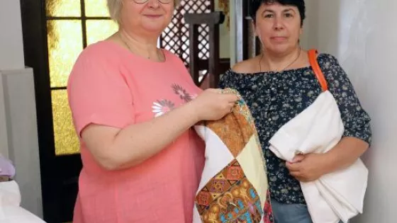 Two women holding comforters