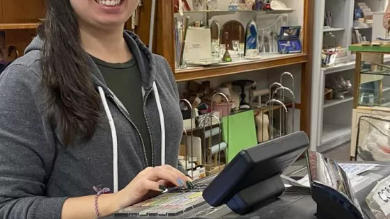 A young woman stands at the cashier station at a thrift shop