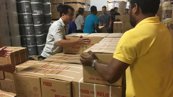Two young men stack boxes that say "food for relief"