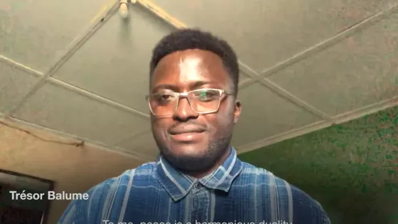 A young Zambian man in a blue plaid shirt with glasses.