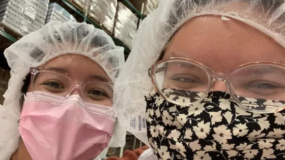 Two young women wearing hair nets in a warehouse