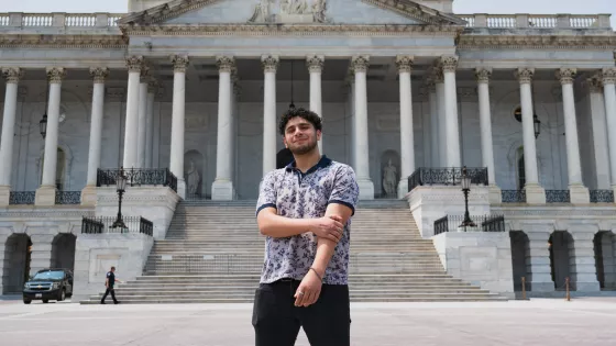 A young adult stands in front of the U.S. capital building