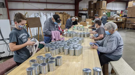 Group of volunteers putting labels on cans.