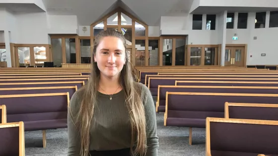 A young woman stands in a church sanctuary