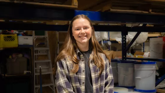 A smiling young woman in front of relief buckets.