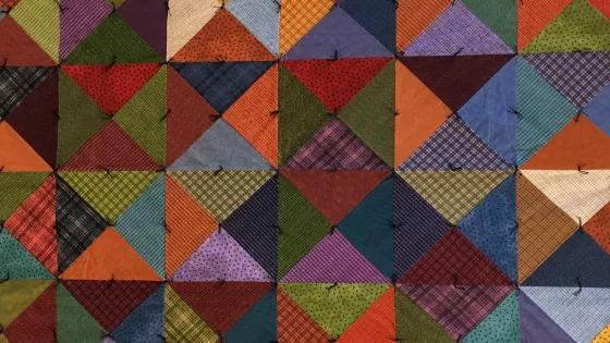 A photo of a colorful quilt made with squares and triangles.