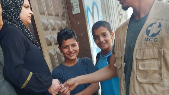 A man handing relief supplies to a woman and two boys