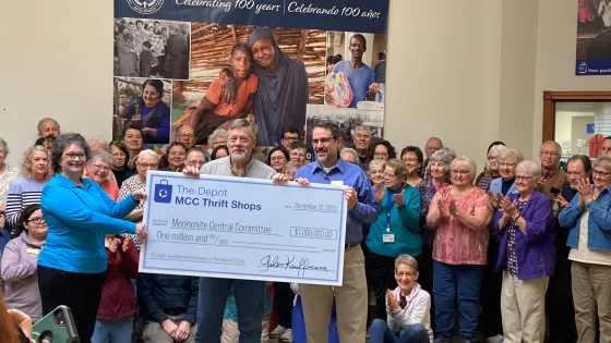 three people hold large check for $1 million while crowd looks on