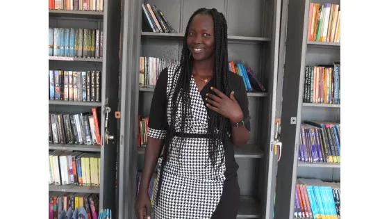 A woman stands in front of a bookcase