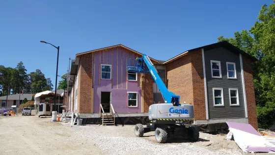 Two story apartment building under construction with a blue crane in front