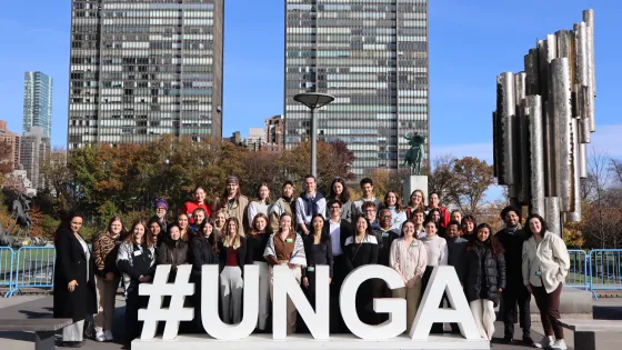 Students gather in front of the United Nations General Assembly sign. 