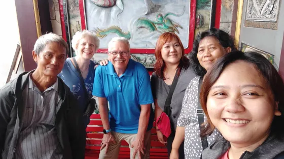 A U.S. couple stands with four other people in front of a mural with a dragon on it.