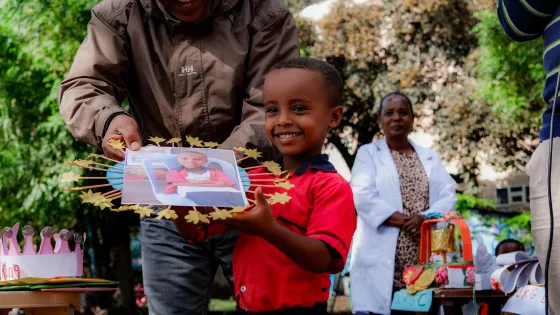 Five-year-old Sudeyis Sherif, collects his award for standing 1st in his nursery school class from MCC staff Solomon along at the morning assembly cermony of RPC Preschool, Adama Ethiopia, March 2024.