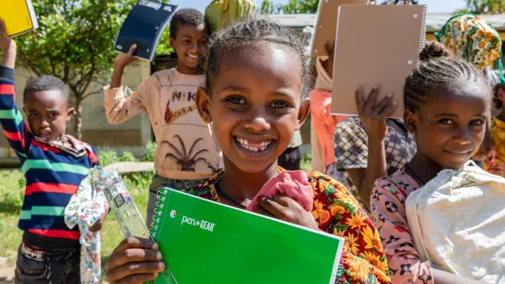 Monaliza Luel, center, and other children including Adonai Melese, left, and Melite Aregawi, right, at Daero Tekli Elementary School, hold their school supplies for a photo after receiving them in late September.