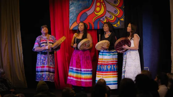  A group of Indigenous women drumming on a stage