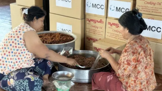 two women preparing food in front of stacks of boxes