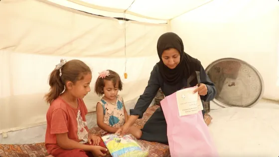 Nisma opens the care package and hands clothing to her two children.