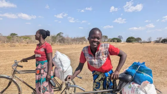 Chiloto Chizongo (right) and Juliet Chabokola (left) stand with their bikes loaded with bags of food provided to them from MCC partners.