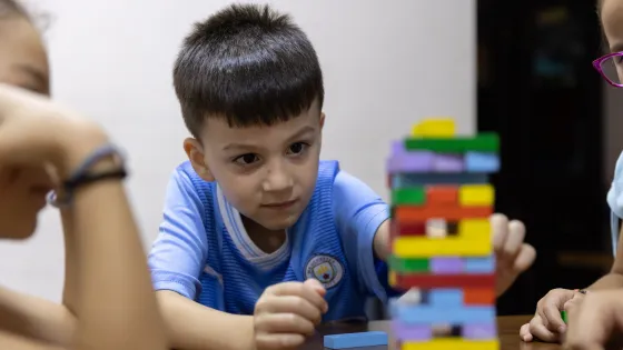 A child in Syria plays with Jenga blocks at a table of his peers.