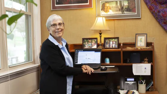 woman sitting in front of desk with a computer and family pictures in the background