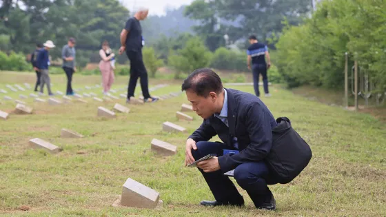 Man looks at a headstone in a cemetery