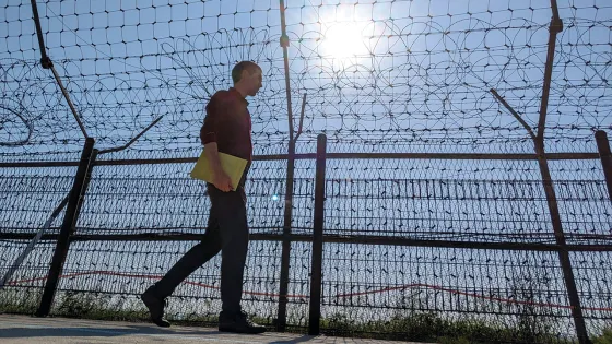 Man walks alongside fencing