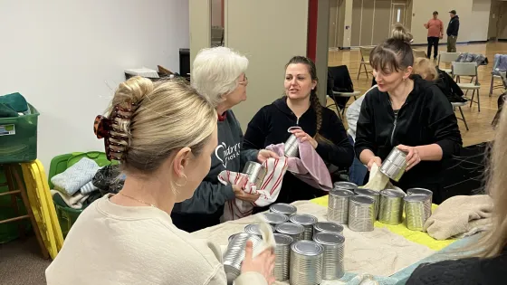women stand and wipe cans of meat with cloths