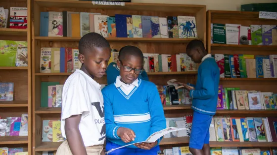 Jean d'Amour Iravuze, left, and Bruno Ineza Kabera read a book at the Gicumbi Children's Peace Library, operated by Transformational Leadership Center. Books are organized into categories like easy fi