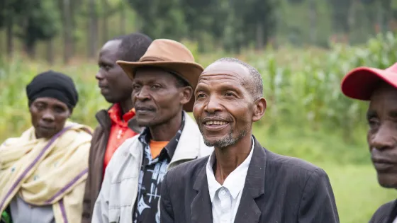 Members of a farmer field school in Rwanda’s Burera District greet staff from MCC, Peace and Durable Development (PDD) and Peace and Development Network (PDN) with song and dance.