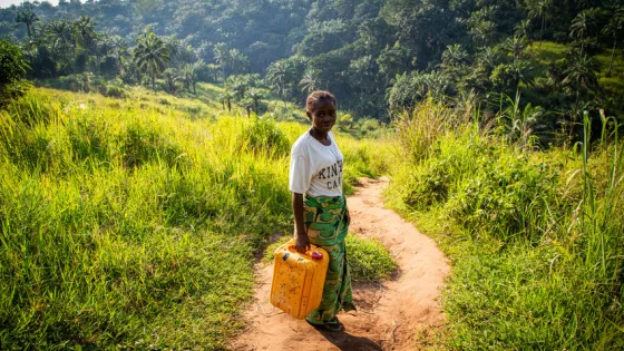 Germaine Kambundi, a widow and mother of five children, shows the walking path she and her children needed to use to collect water from a contaminated spring.