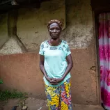  Marie Jeanne Kudimuka, 65, stands outside her home.